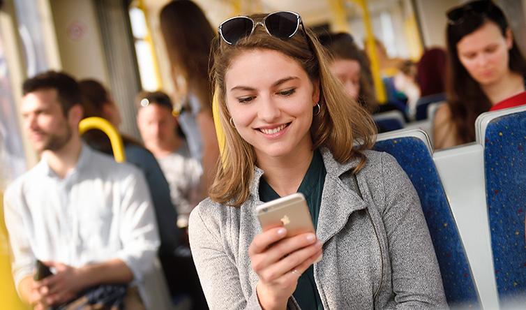 Fahrgast sitzt in der Badner Bahn mit Handy